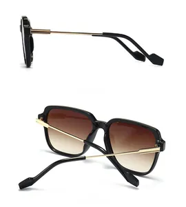 Dettagli di occhiali da sole oversize con stanghette in metallo dorato e lenti sfumate