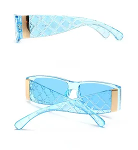Detail view of transparent blue rectangular sunglasses with gold hinges and woven texture