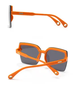 Detail view showing orange frame sunglasses with dark lenses and gold temple accents