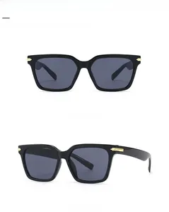 Détail des lunettes de soleil carrées noires avec charnières en métal doré et verres