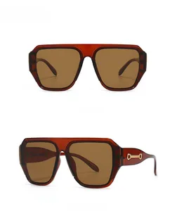 Détail des lunettes de soleil carrées ambre montrant les ornements métalliques dorés