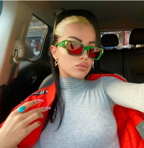 Detail of green square sunglasses with red lenses and gold temple accent on model