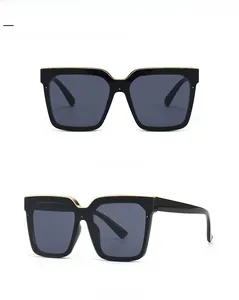 Detail of oversized square cat-eye sunglasses with gold metal trim and dark grey lenses