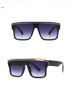 Detail of oversized flat top sunglasses with gold metal trim and grey gradient lenses