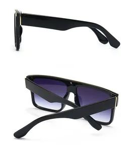 Detail view of black frame sunglasses with gold metal top bar and purple gradient lenses