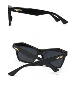 Detail of black cat-eye sunglasses with golden metal stripes on the temples