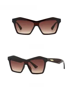 Detail of tan cat-eye sunglasses featuring golden metal bar accents on the temples