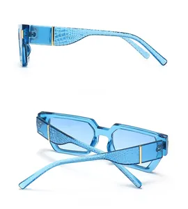 Detail view of blue transparent square sunglasses with golden metal crocodile texture arms