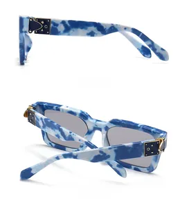 Détail de lunettes de soleil marbré bleu avec charnière en métal doré et ornements rivets