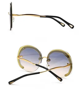Side and back view of oversized round sunglasses with wavy gold metal frames and blue lenses