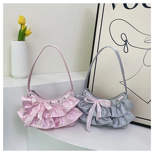 Detailed shot of satin shoulder bags with ruffle trim and ribbon bows in pink and grey