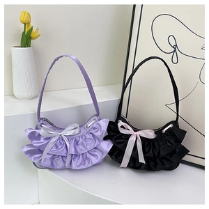 Close-up of ruffled satin handbags with ribbon bows in lavender purple and classic black