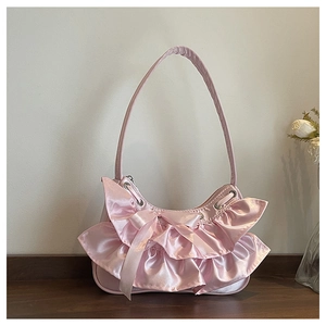 Detail of pink satin shoulder bag featuring ruffled lace design and silk bow accent