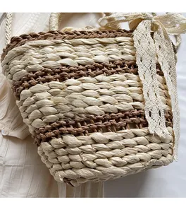 Detailed close-up of handmade woven straw bucket bag with elegant white lace ribbon knot