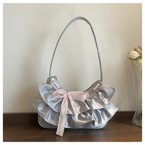 Close-up of a satin shoulder bag featuring ruffled lace edges and a pink ribbon bow