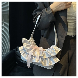 Detail showing ruffled satin texture and a pink silk bow on the silver shoulder bag