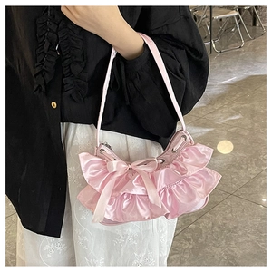 Detail of pink silk shoulder bag featuring ruffle pleats and a decorative ribbon bow