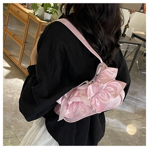 Detail of pink satin shoulder bag featuring layered ruffles and a silk bow accent