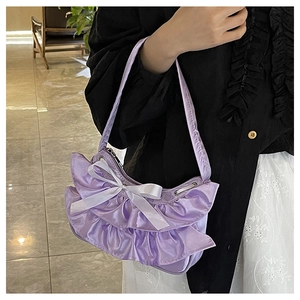 Detail of purple ruffled shoulder bag with white ribbon bow and soft pleated silk fabric