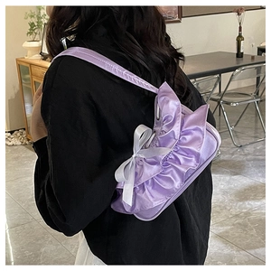 Detail of light purple satin shoulder bag with ruffled edges and white bow decoration