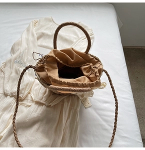 Close-up of straw bucket bag featuring lace details and drawstring lining on white fabric