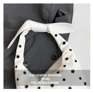 Detail view of white tote bag with metal eyelets and adjustable knotted strap feature