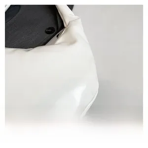 Detail shot of white glossy PU leather shoulder bag featuring stylish side pleats