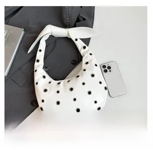 Detail view of white leather shoulder bag with silver eyelets and oversized bow knot