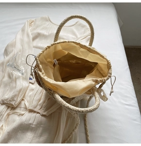 Overhead view of a woven straw bucket bag with drawstring liner and internal pockets