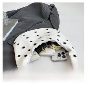 Interior capacity of white studded crescent bag showing phone and cosmetics details