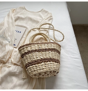 Close-up of woven straw bucket bag showing striped texture and round handle details