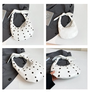 Detail showing white half-moon bag with silver grommets and stylish bow handle
