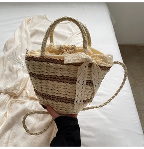 Detail of hand-woven straw bucket bag with lace bow and drawstring closure