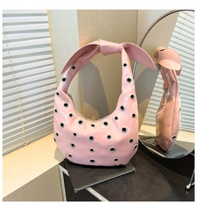 Detail of pink leather handbag featuring oversized silver eyelets and large top knot strap