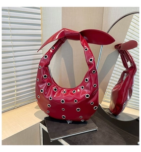 Macro shot of red patent leather tote with silver eyelets and a decorative bow design