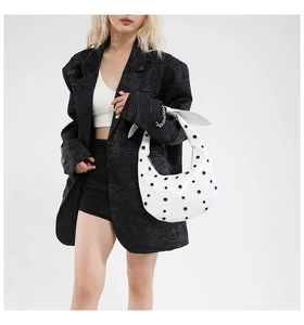 Close-up of white crescent underarm bag with grommet decor and oversized shoulder knot