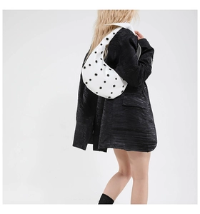 Detailed view of white eyelet hobo bag with metal grommets worn on the shoulder