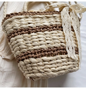 Detailed view of bicolor straw woven bag featuring elegant lace bow and texture