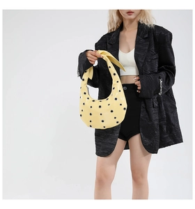 Detail of bright yellow crescent tote bag featuring metallic silver eyelets and smooth finish