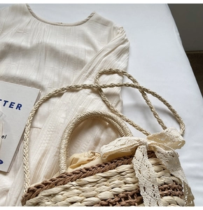 Detail of hand-woven straw bucket bag with white lace bow and drawstring inner lining