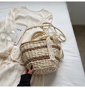 Detail of woven straw bucket bag with cream lace bow and leather stitching accents