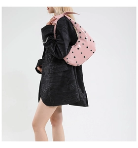 Pink underarm tote bag with silver metal eyelets and glossy leather on black blazer