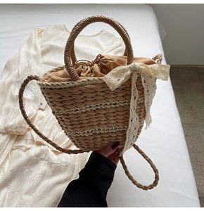 Close-up of handwoven straw bucket bag with delicate lace bow and drawstring inner lining
