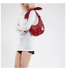 Detailed side view of red patent leather hobo bag with eyelets and large bow on model