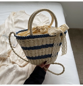 Detail of woven straw bucket bag featuring blue stripes and sweet lace bow decoration