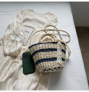 Close-up of woven straw bucket bag featuring blue stripes and lace bow on dress
