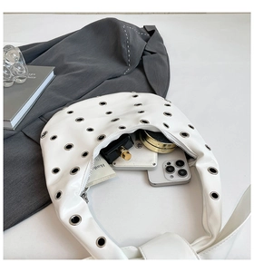 Detail showing the spacious interior of a white crescent shoulder bag with essentials