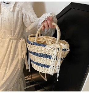 Close-up of woven straw bucket bag with blue stripes and elegant lace bow detail