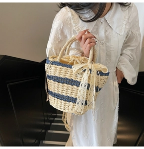 Close-up of woven straw bucket bag with blue stripes and decorative lace bow detail