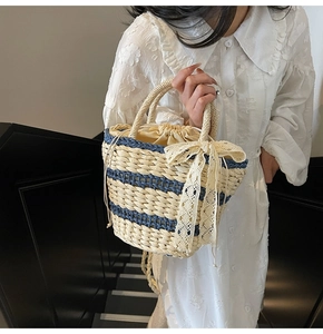 Detail of woven straw bucket bag with blue stripes and delicate white lace bow decoration